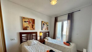 Ein Hotelzimmer mit zwei Betten, einem Fenster mit Vorhängen und Bildern an der Wand.
