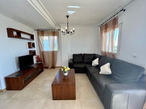 A living room with a sofa, a coffee table, a TV on a wooden stand, and a chandelier. - Apartment with spectacular views - ER4522LT (Torre-Pacheco)