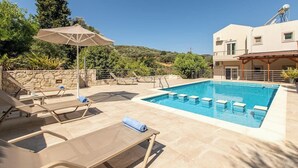 Une piscine avec des chaises longues et un mur en pierre.
