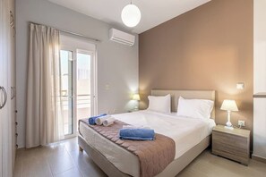 Een hotelkamer met een bed, nachtkastjes, een lamp, een raam met gordijnen en een airconditioning.