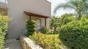Un bâtiment doté d’un mur en pierre, d’une pergola en bois et d’un jardin bien entretenu, agrémenté de diverses plantes et fleurs.