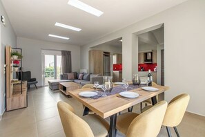 A modern living space with a dining area, kitchen, and a seating area with a view.