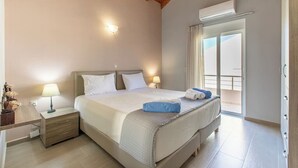 Une chambre d’hôtel comprenant un lit, des lampes de chevet, une table de nuit, une fenêtre avec des rideaux et un appareil de climatisation.