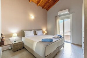 Een hotelkamer met een bed, nachtlampjes, een nachtkastje, een raam met gordijnen en een airconditioning.