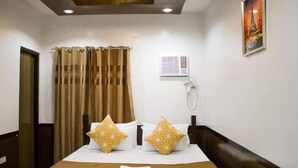 Habitació d'hotel amb un llit, cortines, aire condicionat fixat a la paret i una fotografia emmarcada.