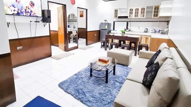 Un saló modern amb un sofà, una taula de centre i un televisor. Hi ha una zona de cuina amb armaris i una taula de dinar.