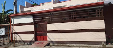 Un edificio con una puerta roja y una rampa que conduce a la entrada.