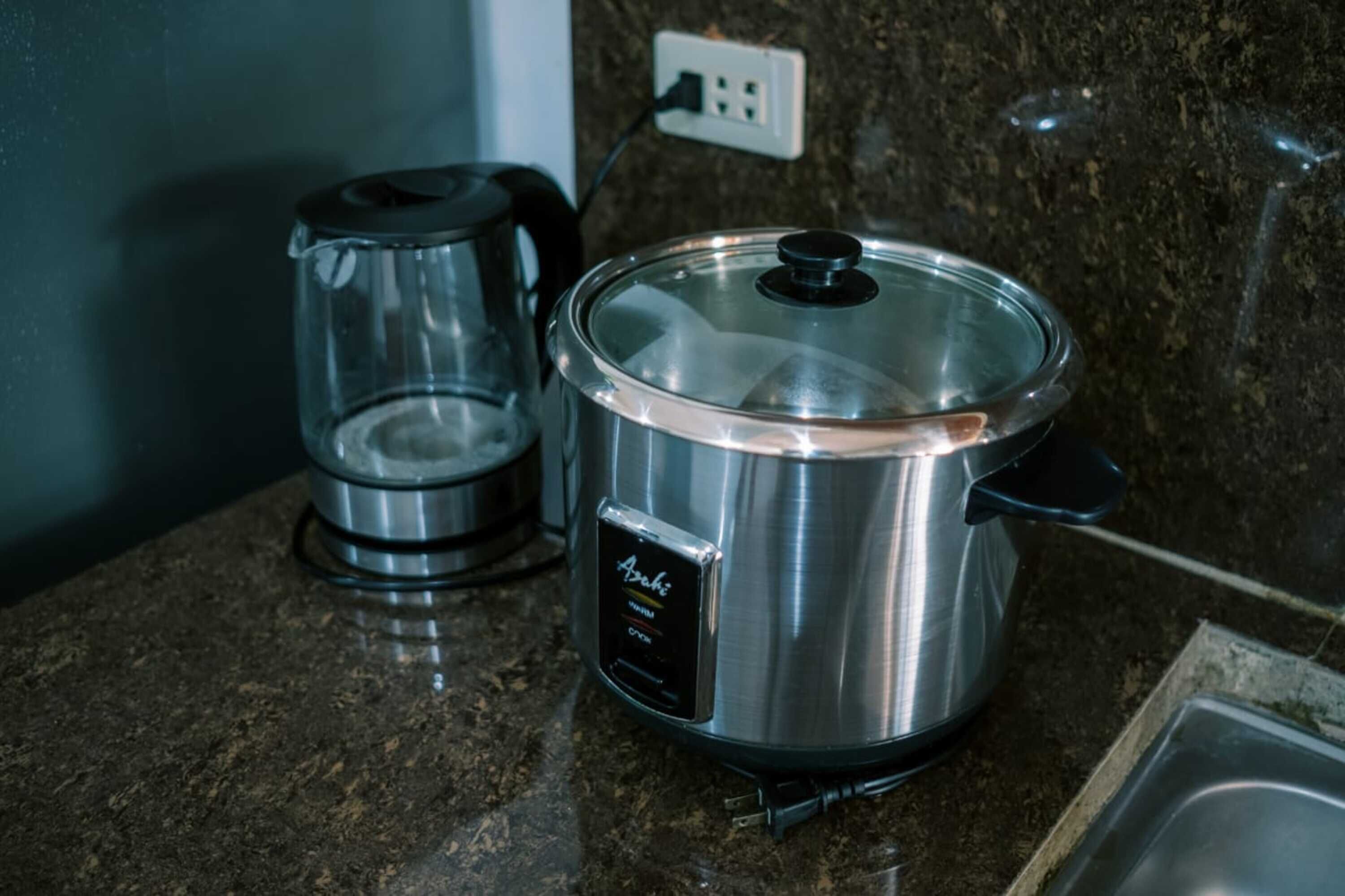 A stainless steel slow cooker on a granite countertop with a coffee maker beside it.