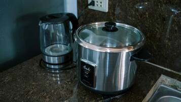 A stainless steel slow cooker on a granite countertop with a coffee maker beside it.