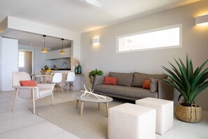 Un salon moderne comprenant un canapé, des fauteuils, une table basse et un coin repas avec des chaises et une table.