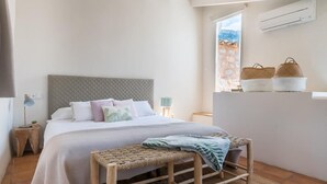 A bedroom with a bed, bedside tables, a bench, and a view of the outdoors.