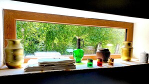 Une fenêtre donnant sur un paysage verdoyant, un vase et une pile de papiers posés sur un rebord.