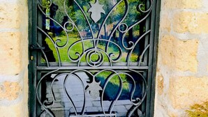 Un portail en fer forgé aux motifs complexes, encadré par une arche en pierre.