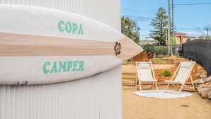 Ein Surfbrett mit dem Aufdruck "COPA CAMPER", angelehnt an eine weiße Wand.