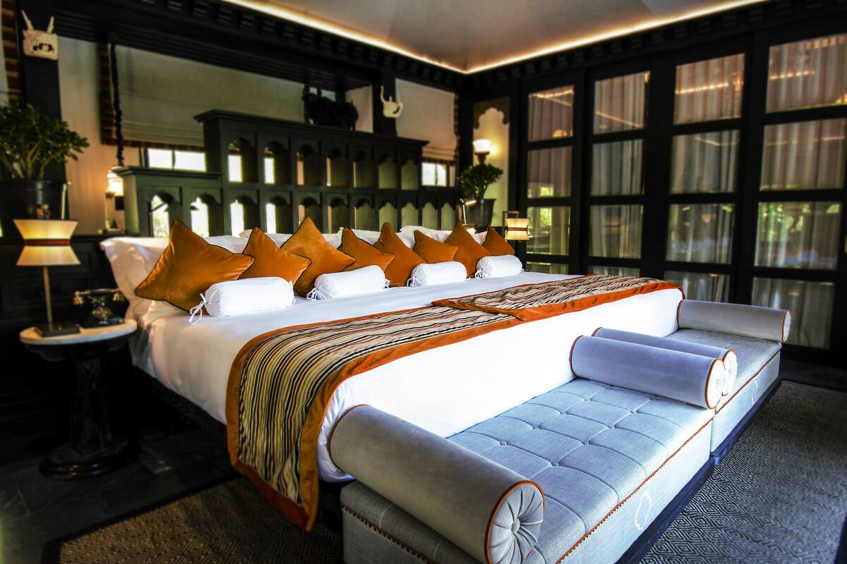 Una habitación de hotel moderna con una cama grande, un sofá y una mesita de noche con una lámpara.
