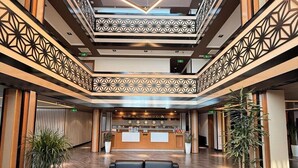 A spacious lobby with a reception desk, seating area, and decorative geometric patterns on the walls and ceiling. - Hotel Bukhara (Bukhara)