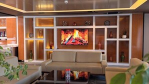 A modern living room with a flat-screen TV, leather sofas, and a coffee table. - Hotel Bukhara (Bukhara)