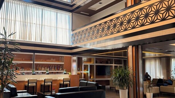 A spacious lobby with a bar area, seating, and large windows. - Hotel Bukhara (Bukhara)