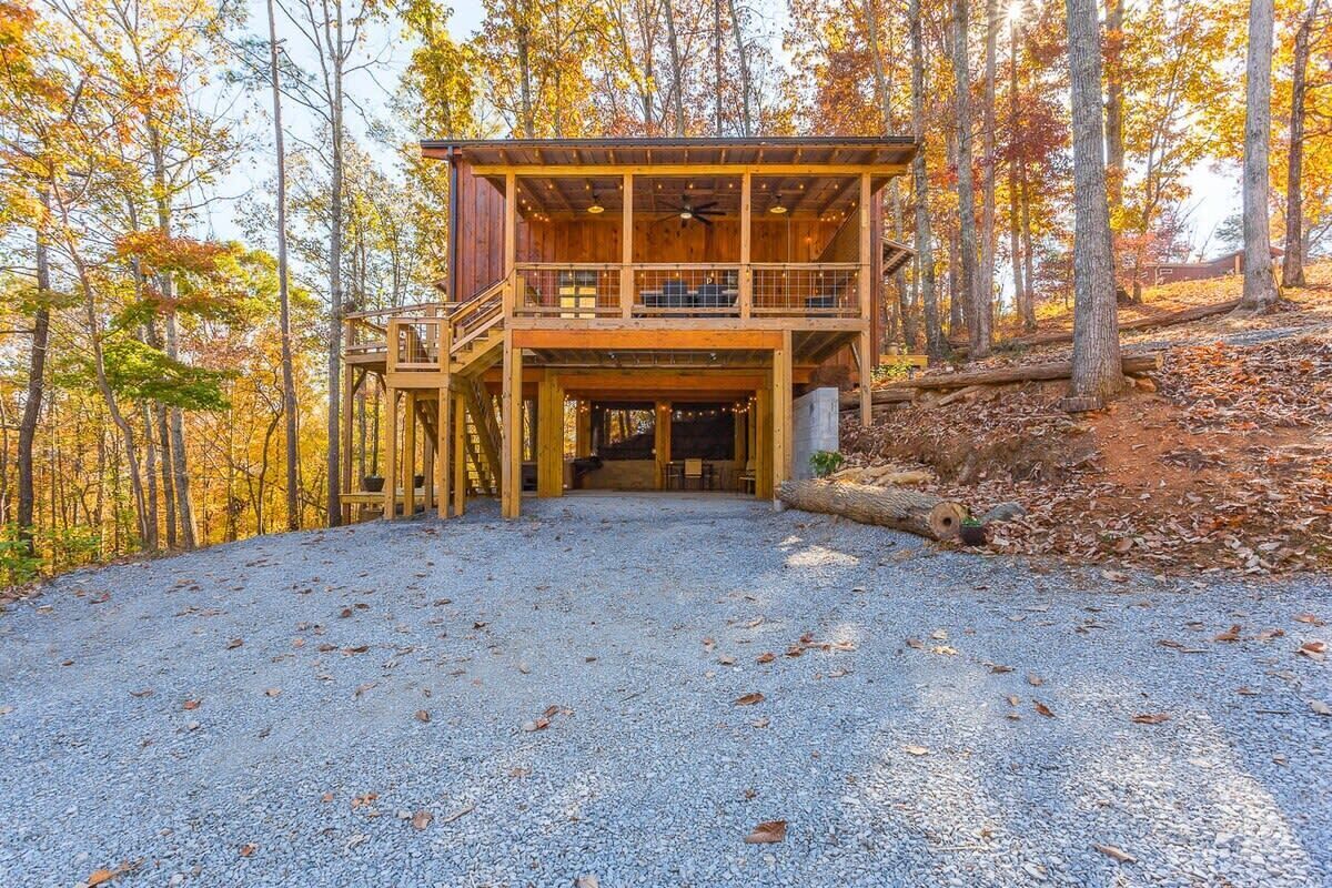 A wooden cabin with a balcony, surrounded by trees.