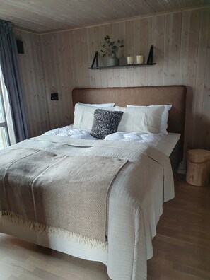 Una cama con cabecera de madera, una mesita de noche y un taburete pequeño de madera.