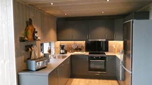 Una cocina moderna con armarios oscuros, electrodomésticos de acero inoxidable y techo de madera.