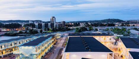 A hotel with multiple floors, a rooftop terrace, and a view of the surrounding cityscape.