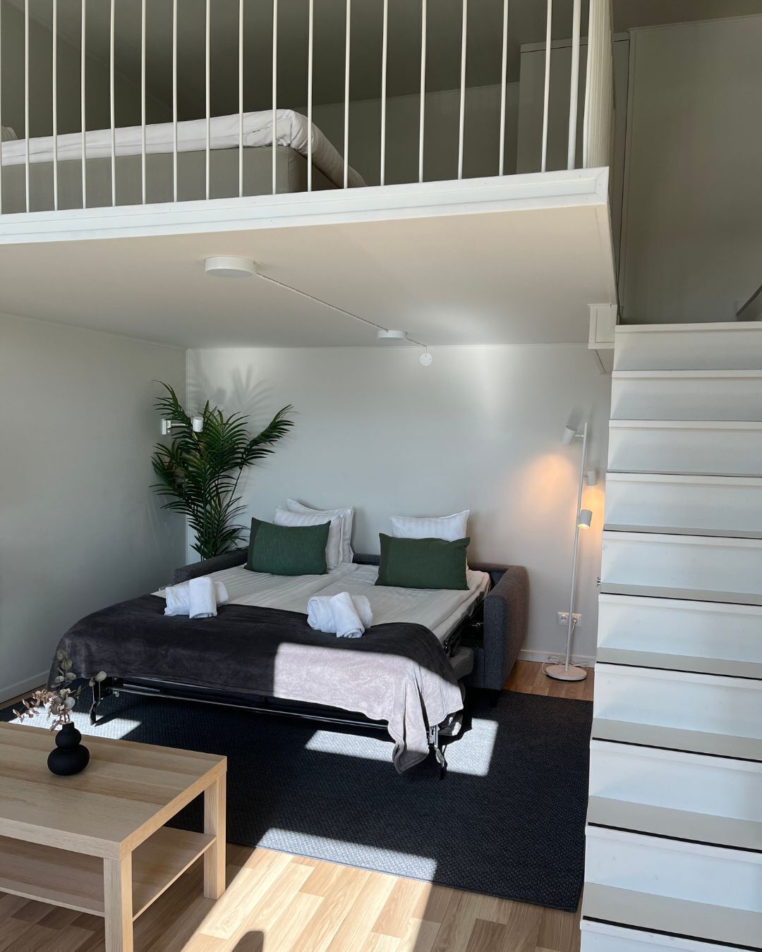 A compact bedroom with a bed, bedside table, and a small desk.