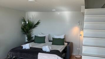 A compact bedroom with a bed, bedside table, and a small desk.