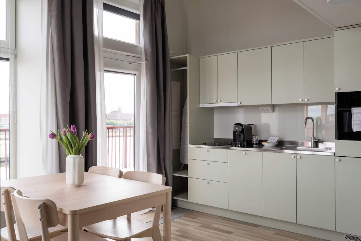 Una cocina moderna con armarios blancos, una mesa de comedor con sillas y un florero con flores.