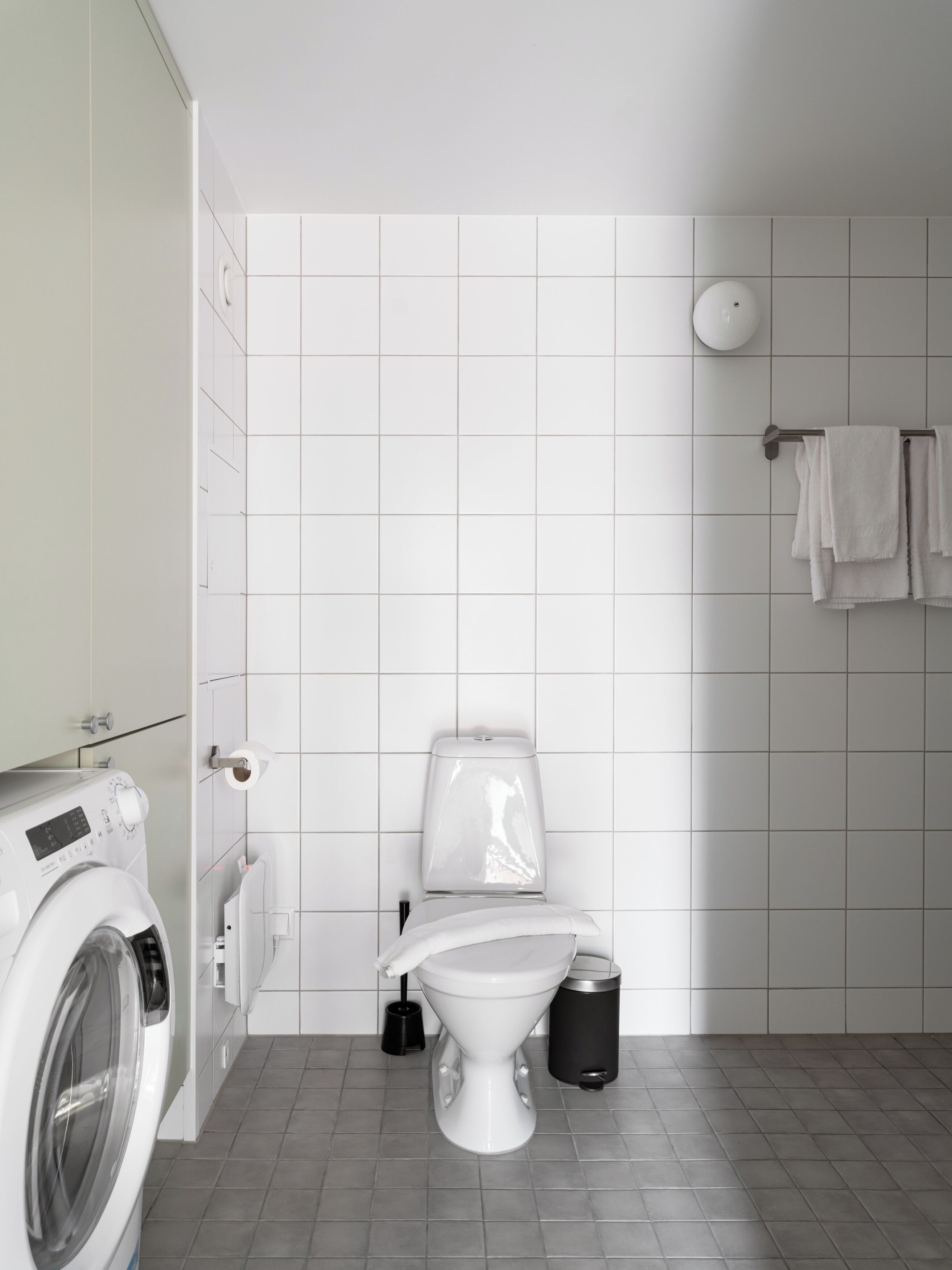 Un baño moderno con inodoro, lavadora y paredes con azulejos.