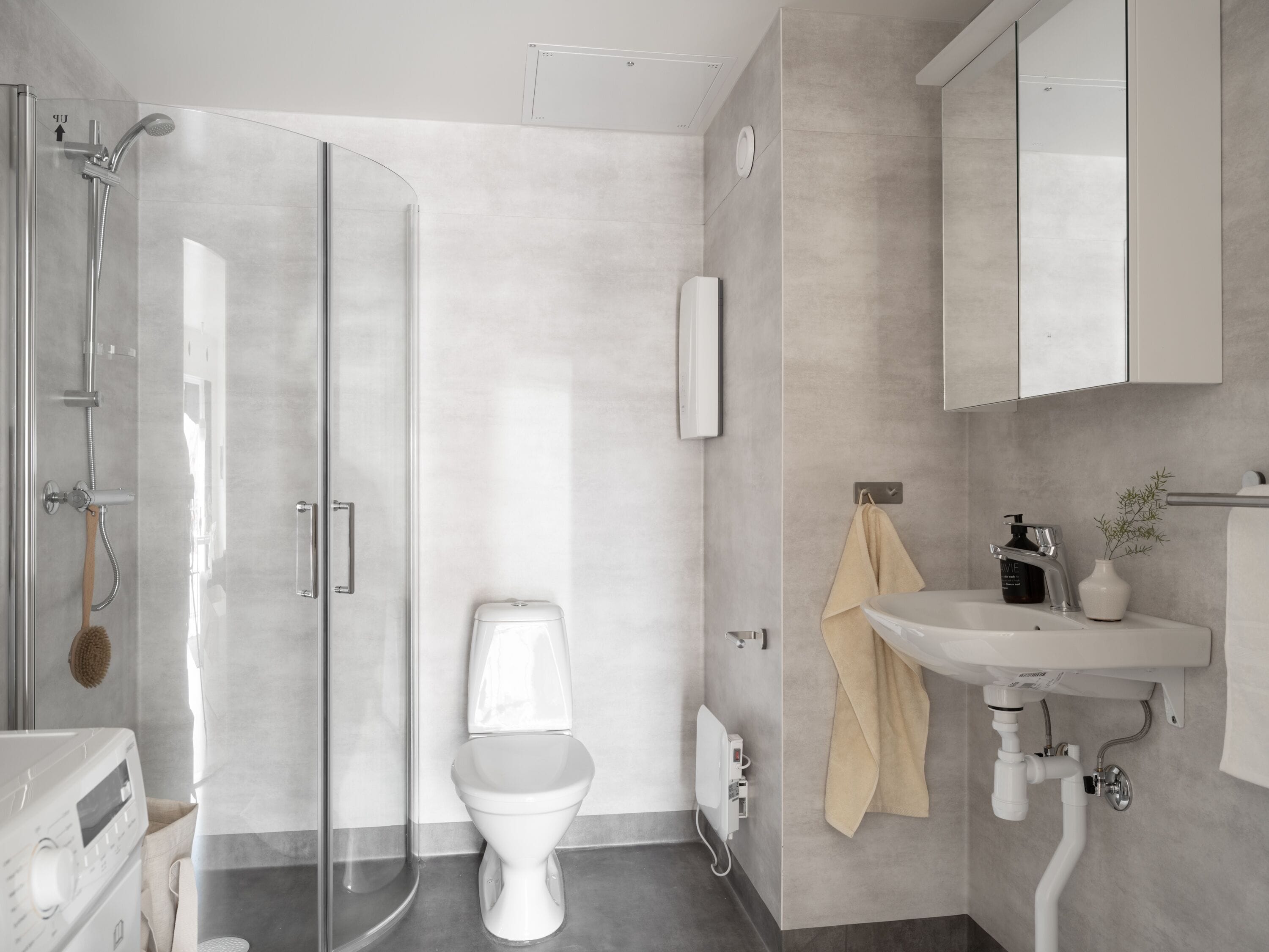 Un baño moderno con cabina de ducha de vidrio, inodoro, lavabo y espejo.