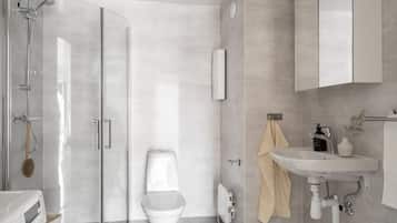 Un baño moderno con cabina de ducha de vidrio, inodoro, lavabo y espejo.