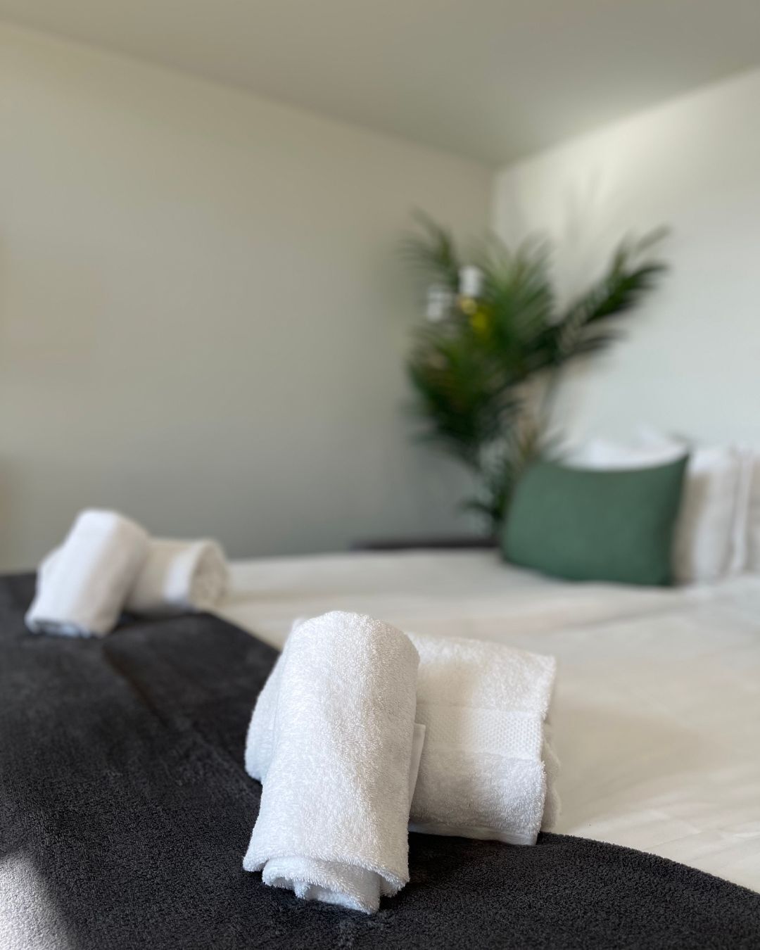 A neatly made bed with white towels and a dark-colored headboard.