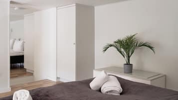 A modern bedroom with a bed, a bedside table, a potted plant, and a wardrobe.