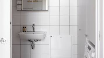 Een moderne badkamer met een wit wastafelmeubel, spiegel en een ingebouwde wasmachine.