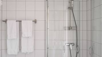 Une douche avec un pare-douche en verre, une pomme de douche à main et un robinet à main.