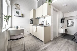 A modern kitchen with white cabinetry, a dining area with a chair, and a small island with a sink.