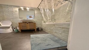A bathroom with a white toilet, a sink with a mirror above it, and a shower with a transparent curtain. - Grand 3 Pieces Lumineux, Lodi (Marseille)