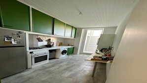 A compact kitchen with green cabinets, a white refrigerator, a stove, a washing machine, and a small table with various items. - Grand 3 Pieces Lumineux, Lodi (Marseille)