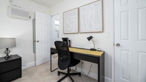 A room with a desk, chair, lamp, and artwork on the wall. - The Heart of Wilton #5 (Wilton Manors)