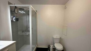 Une petite salle de bain avec une douche, des toilettes et un lavabo.