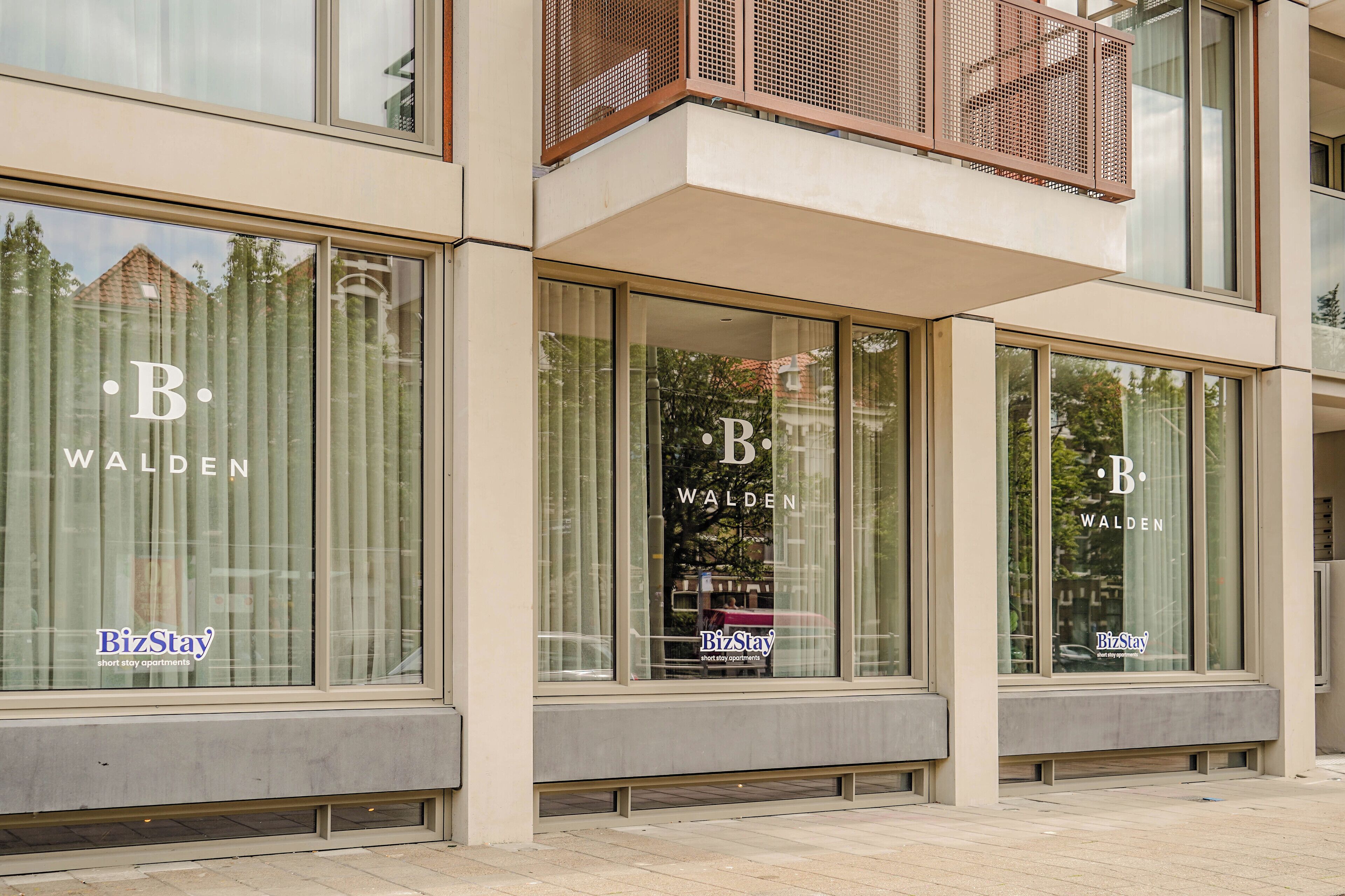 A modern building with large windows labeled "B. Walden" and "BizStay short stay apartments."
