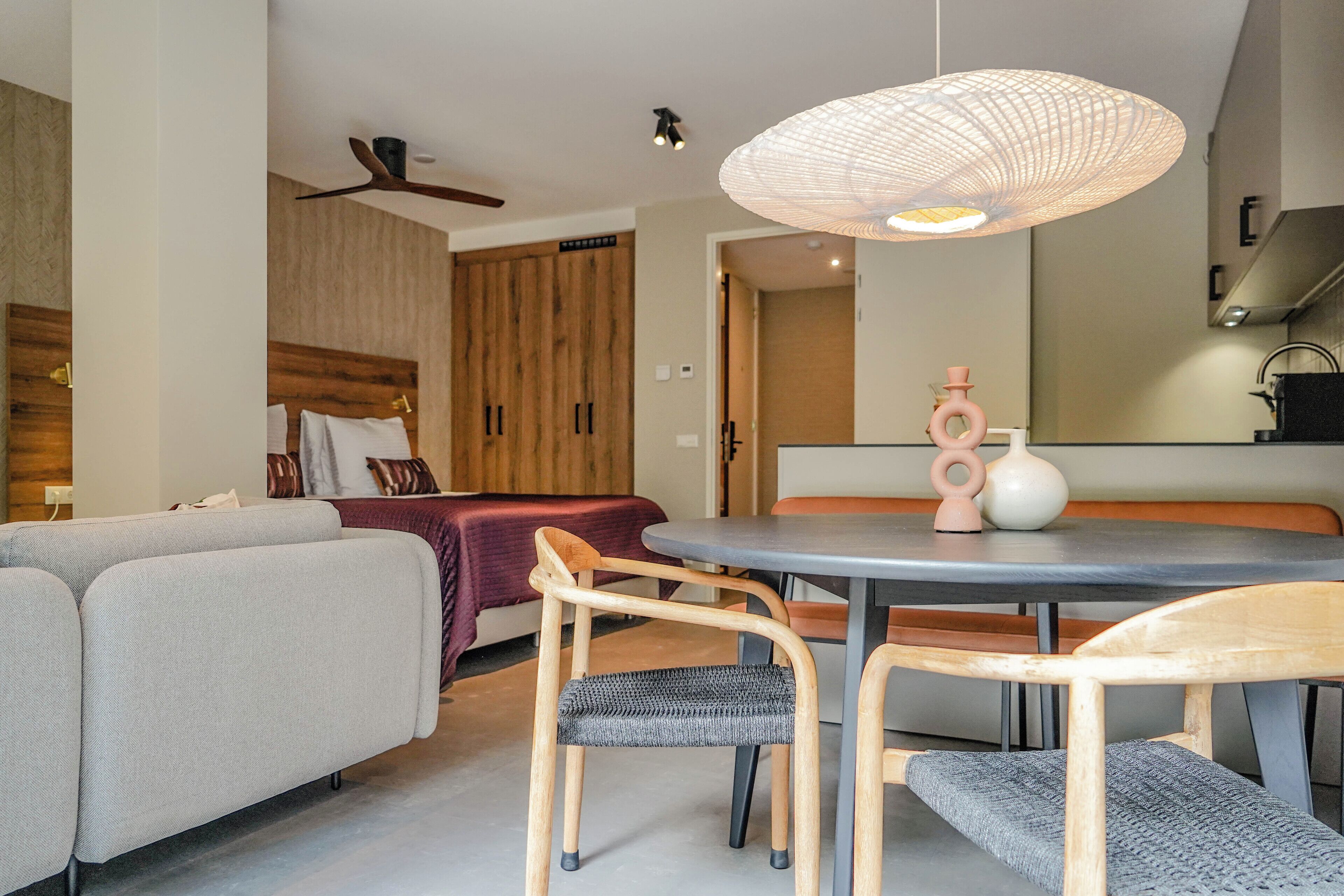 A modern living room with a sofa, chairs, a dining table, and a kitchen area in the background.