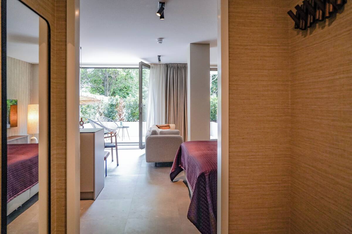 A hotel room with a bed, a desk, a chair, and a view of the outdoors.