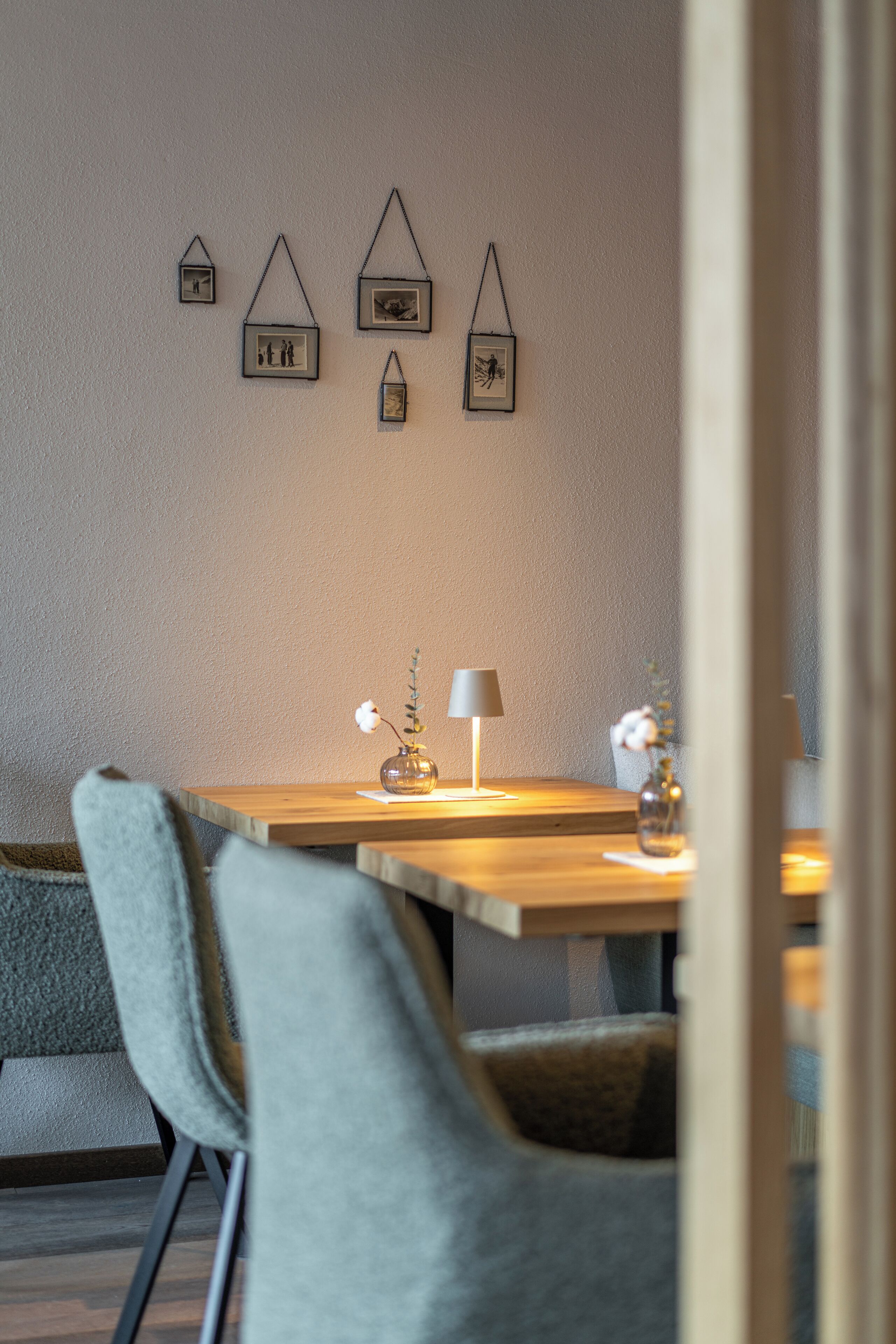 Ein Essbereich mit einem Holztisch, zwei Stühlen, einer Blumenvase und Bilderrahmen an der Wand.