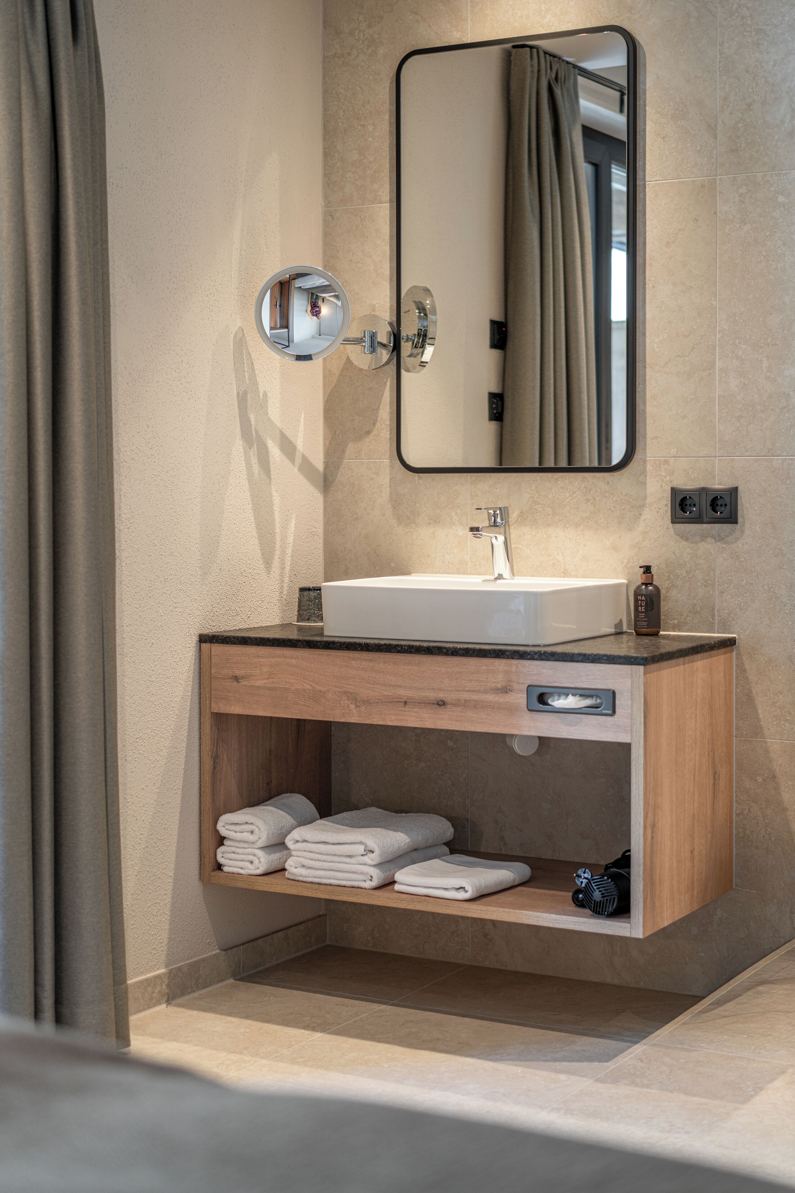 A modern bathroom with a sink, mirror, and towel rack.