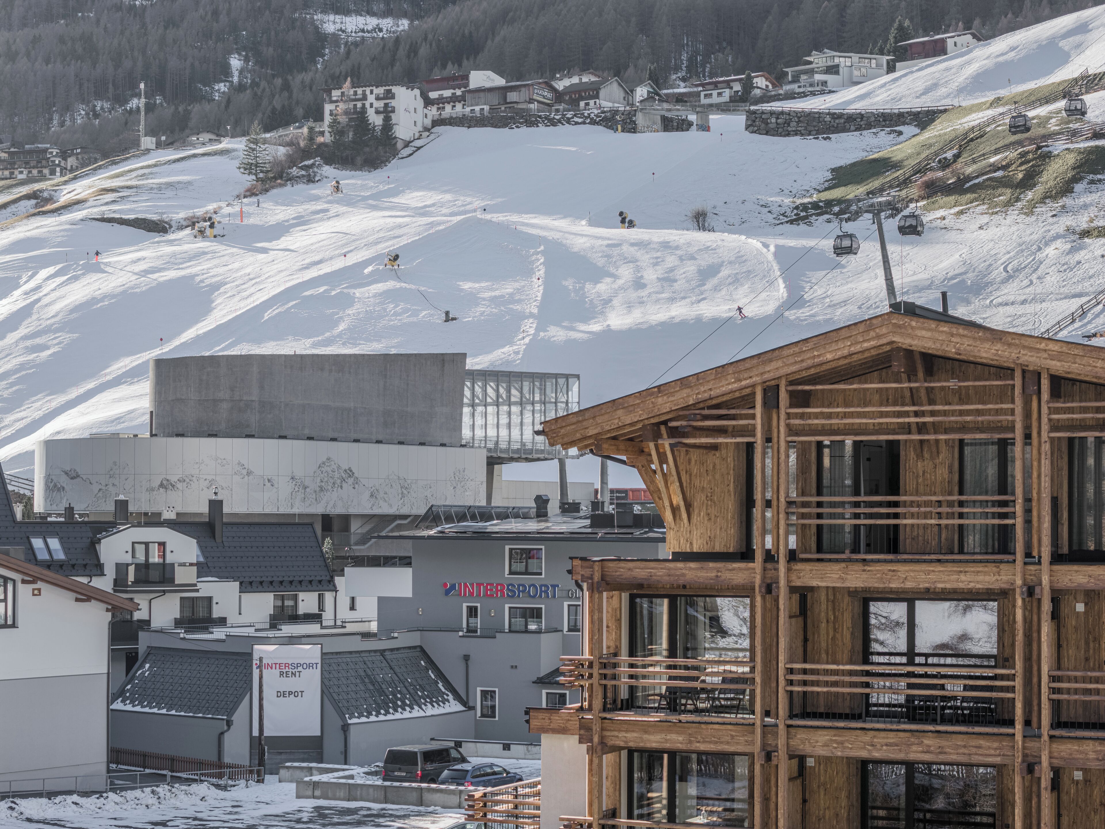 Une station de ski avec un bâtiment en bois portant l’inscription « INTERSPORT » et un panneau indiquant « SERVICE DE LOCATION INTERSPORT ».