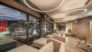 Un moderno vestíbulo de hotel con sofás, sillas de madera y un amplio ventanal con vista a la ciudad.