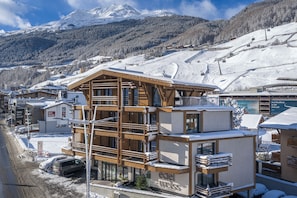 A multi-story hotel with a ski slope in the background, wooden balconies, and a sign for Edel Weiss. - Edelweiss echt.charmant. (Soelden)