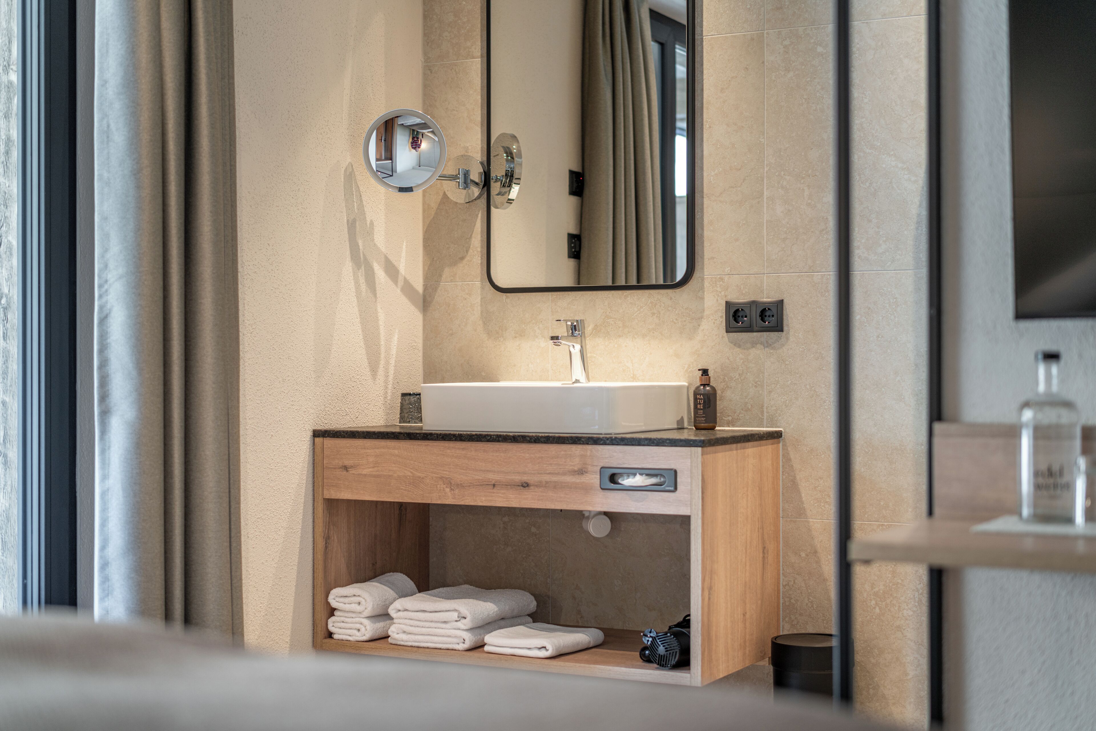 A modern bathroom with a wooden vanity, a sink, and a mirror.